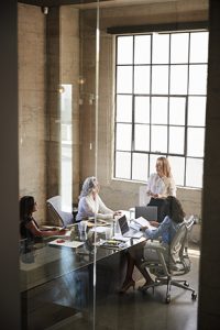 Businesswoman addressing colleagues in meeting, seen through window