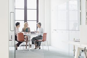 Three women sitting at table in modern office